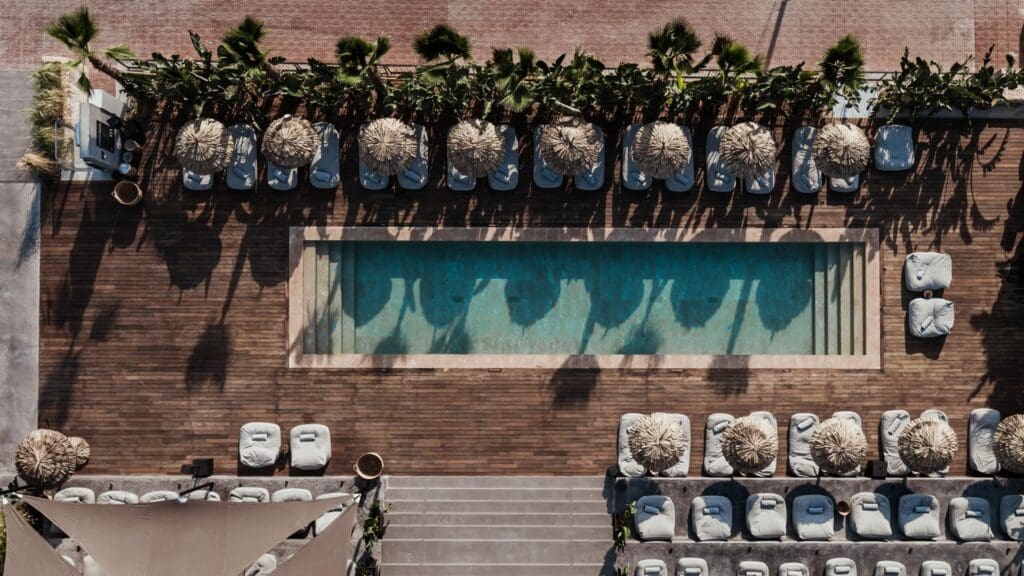 OKU Ibiza pool area in Cala Gració with palm trees, sun loungers and neutral stone styling