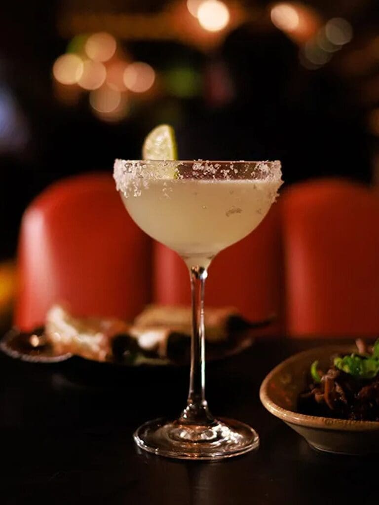 Salt-rimmed margarita with lime wedge served at Kaldero Dublin, photographed against warm low lighting and orange leather seating during a lively hen weekend dinner.
