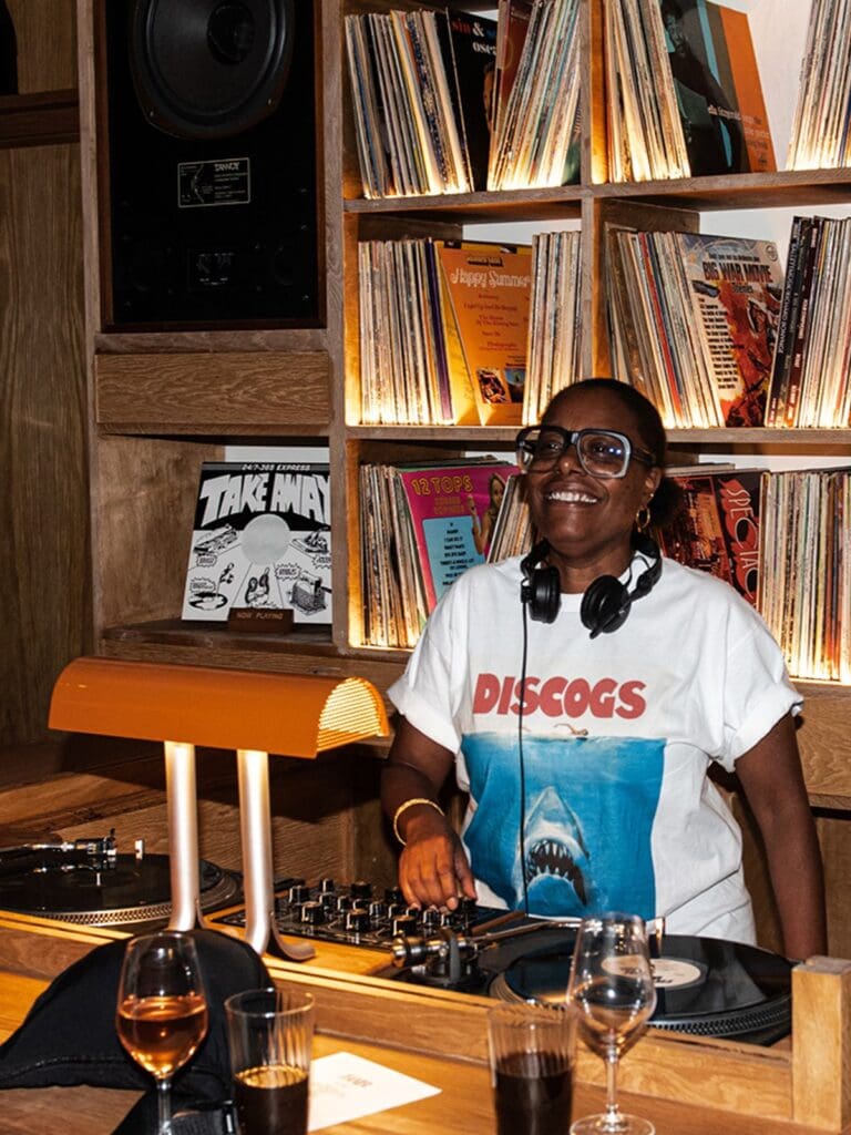 Resident DJ spinning vinyl at Bambi London, surrounded by record shelves and warm, low lighting.