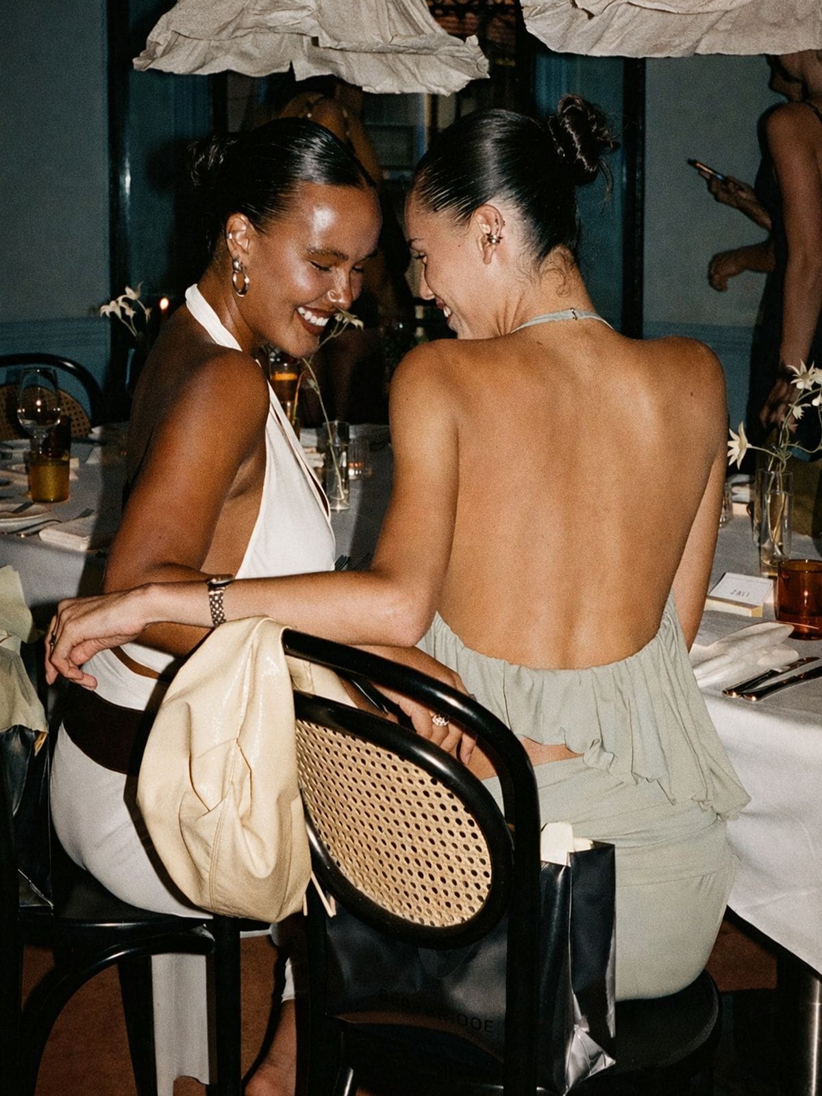 Guests celebrating at a stylish London restaurant in statement evening dresses, photographed with flash lighting — the ultimate London hen weekend dinner vibe.