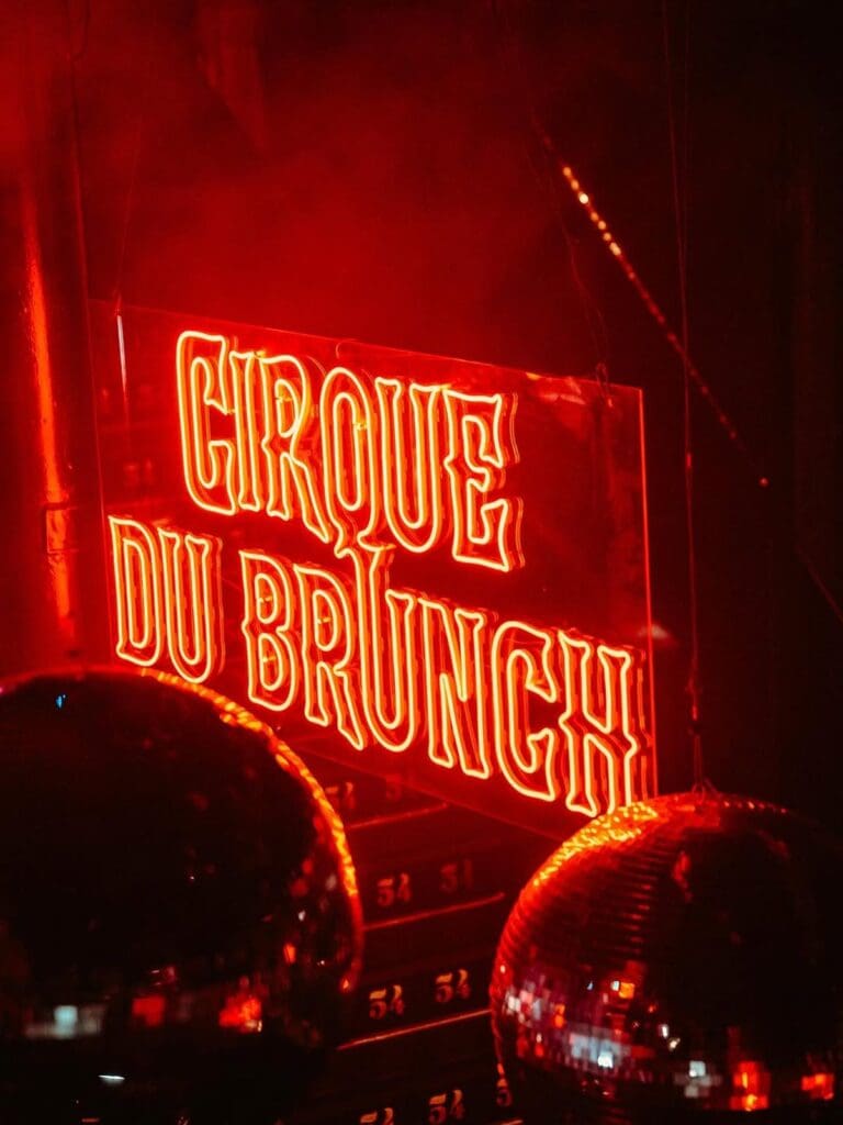 Neon Cirque du Brunch sign glowing red beside disco balls at Cirque du Brunch Liverpool, a hen weekend-ready bottomless brunch venue.
