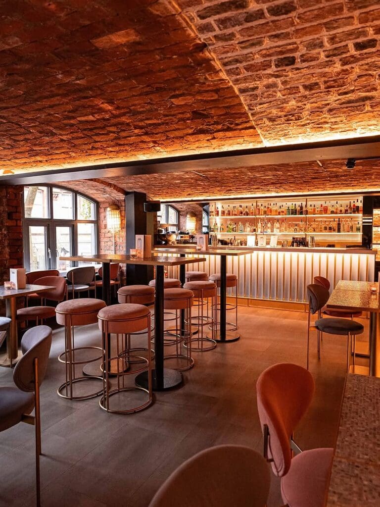 The bar at MAYA Manchester with moody lighting, exposed red brick and a polished cocktail-led vibe on Canal Street.