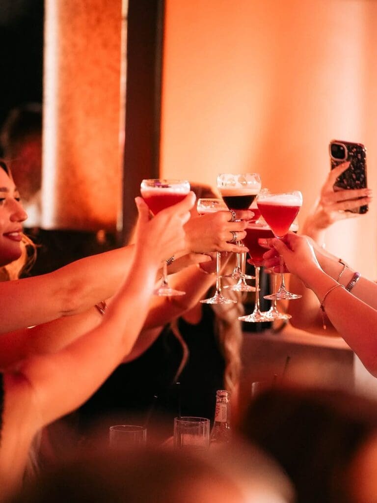 Hen party brunch moment at MAYA Manchester with girls clinking glasses in a moody, low-lit setting.
