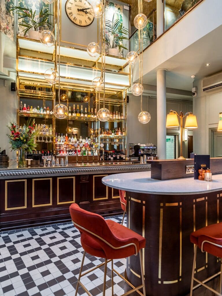 Elegant brasserie-style dining room with high ceilings, polished tables and champagne-style brunch drinks set up for a hen weekend in Bath.