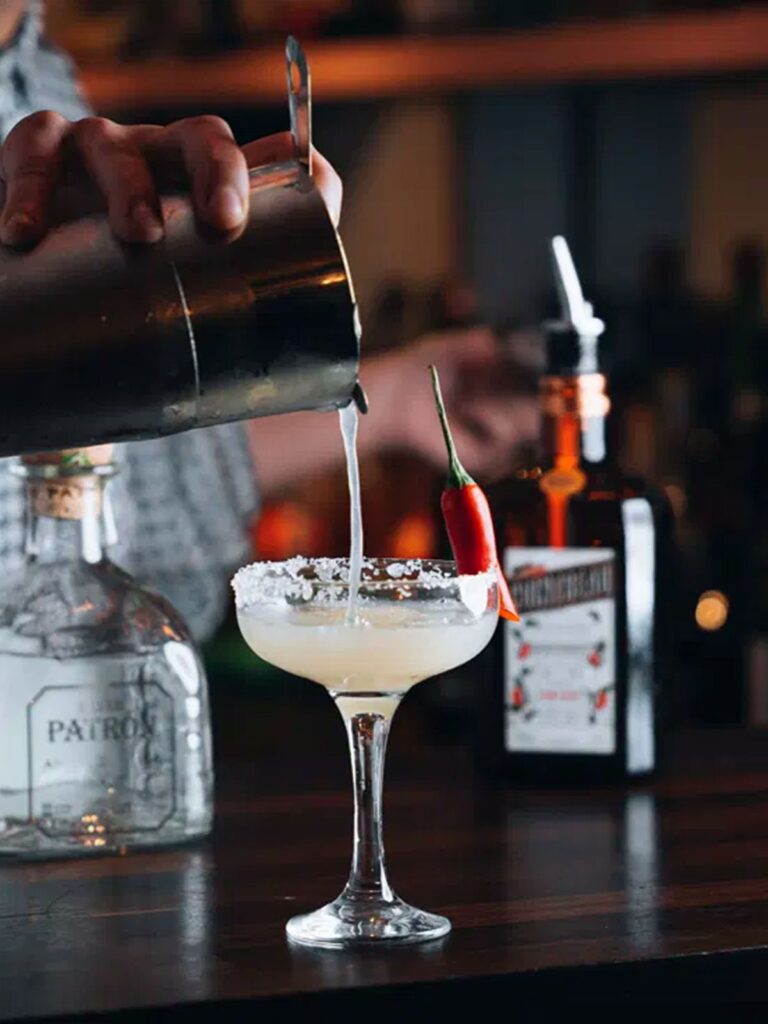 A bartender pouring a bright cocktail/sangria-style drink at Brisa with glasses and small plates on the bar, a Brighton girls’ weekend moment in the making.