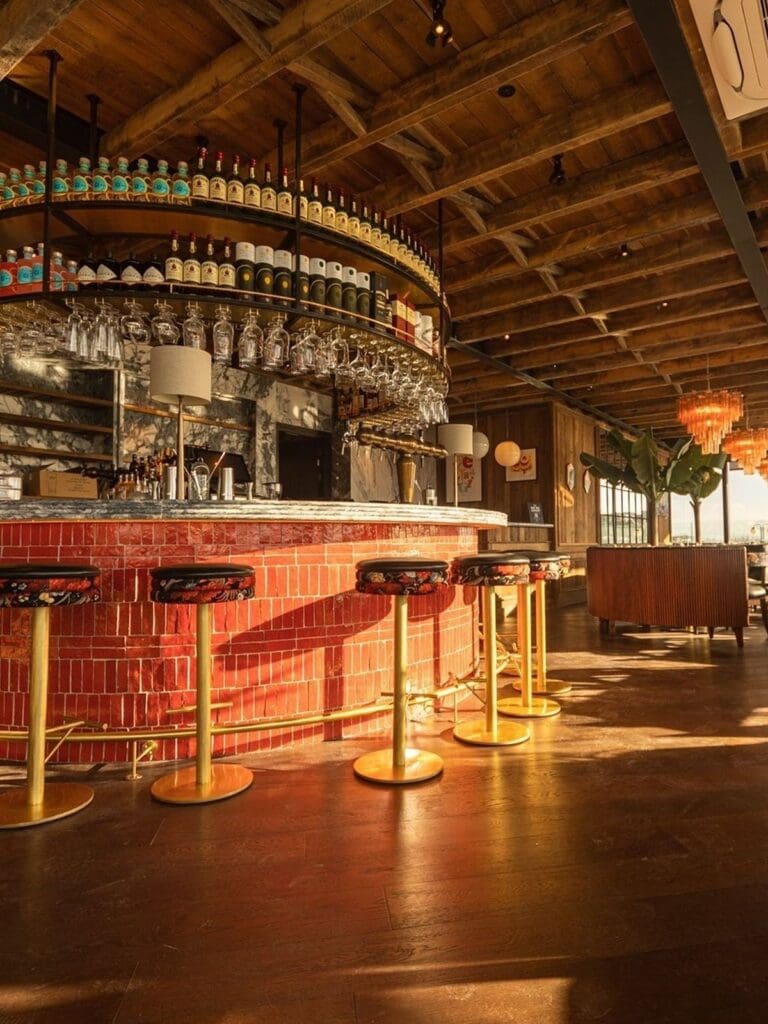 Rooftop bar at Sophie’s Dublin with floor-to-ceiling windows, marble-topped counter and city skyline views, set for cocktails during a lively girls’ night.
