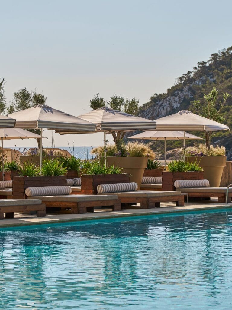 Hyde Ibiza beachfront pool area in Cala Llonga with sun loungers, DJ set-up and sea views.