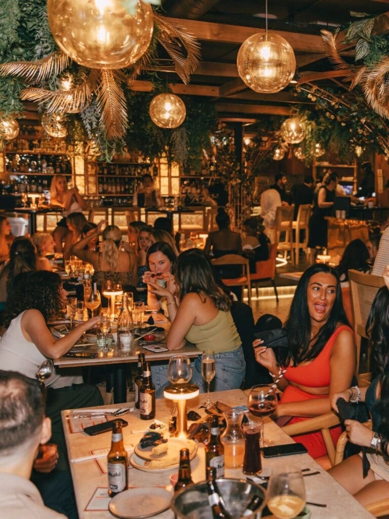 Girls sat at tables at Gura Gura, London, with cocktails and sharing plates, low lighting and a lively dinner-party atmosphere that’s made for a girls’ night or hen weekend.