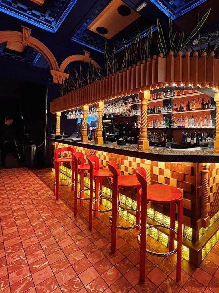 Cabo Edinburgh bar area with red stools, tiled flooring and colourful backlit counter, ideal for a vibey hen weekend dinner.
