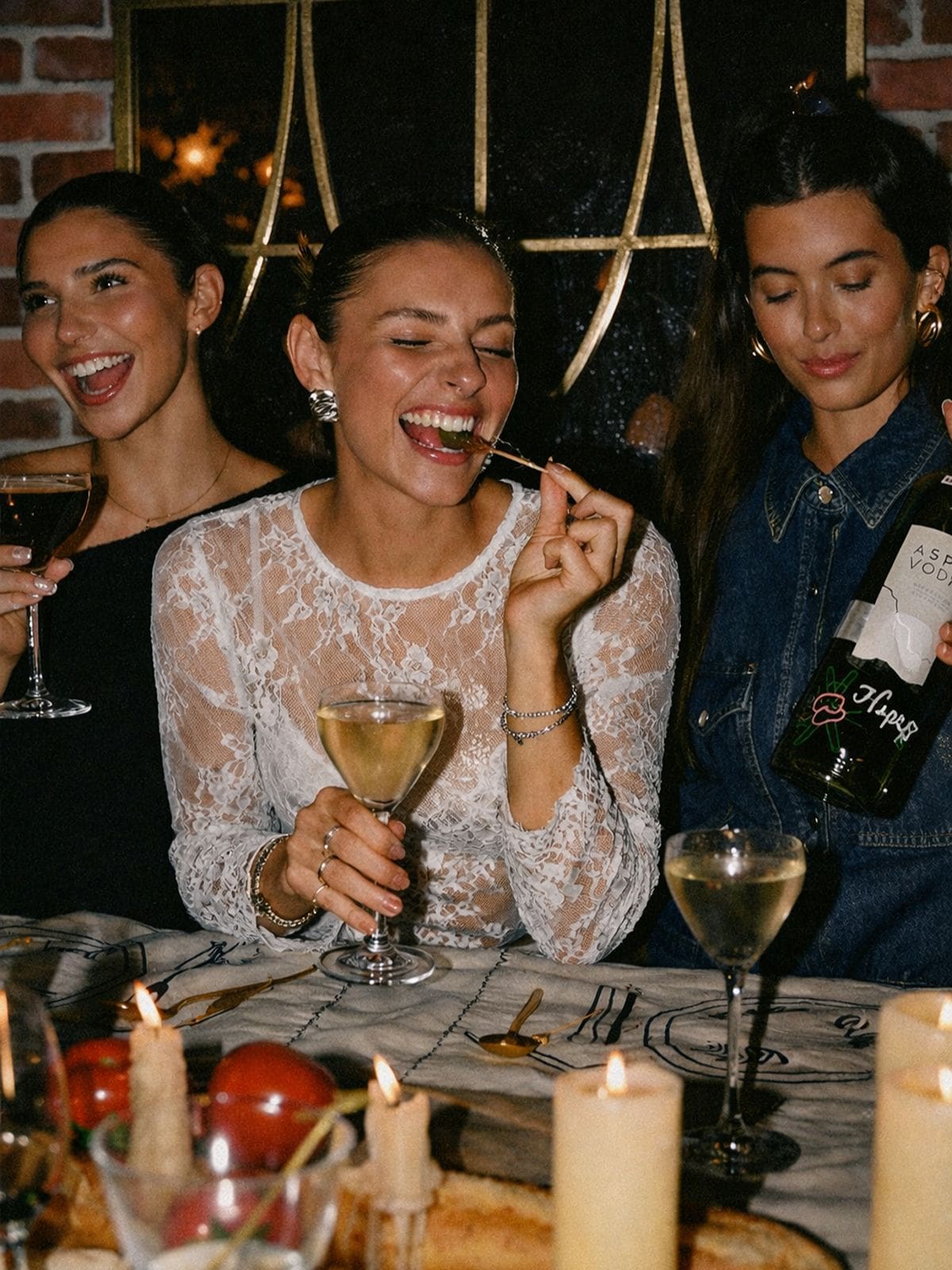 Girls celebrating a hen weekend in Edinburgh, drinking wine and sharing food at a cosy, candlelit dinner table.
