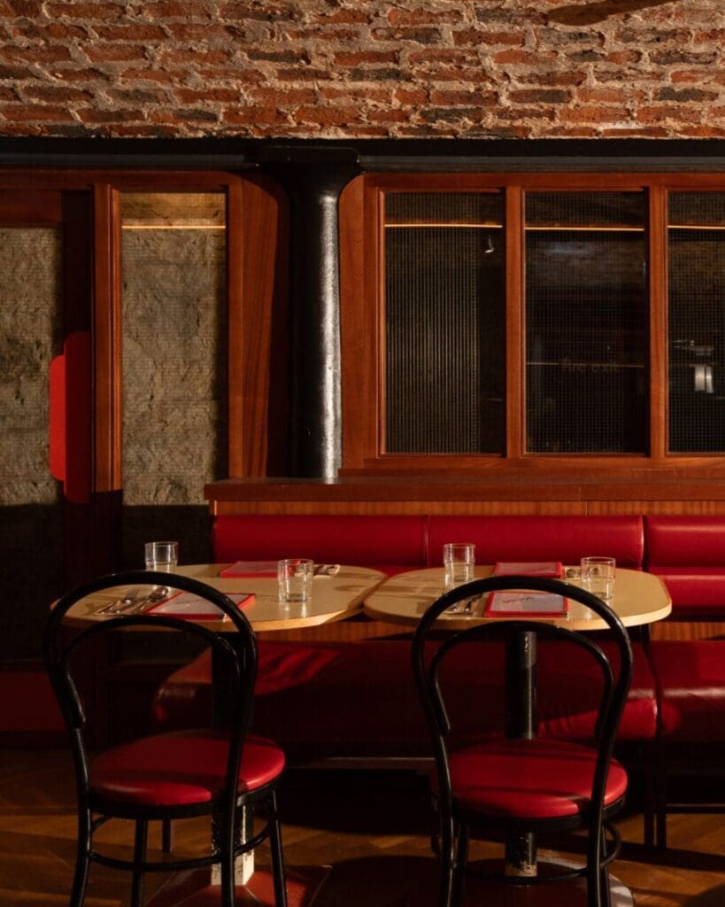 Red leather booth seating inside Sebb’s Glasgow, with exposed brick, warm lighting and retro bistro interiors for a stylish vibey dinner in Glasgow.