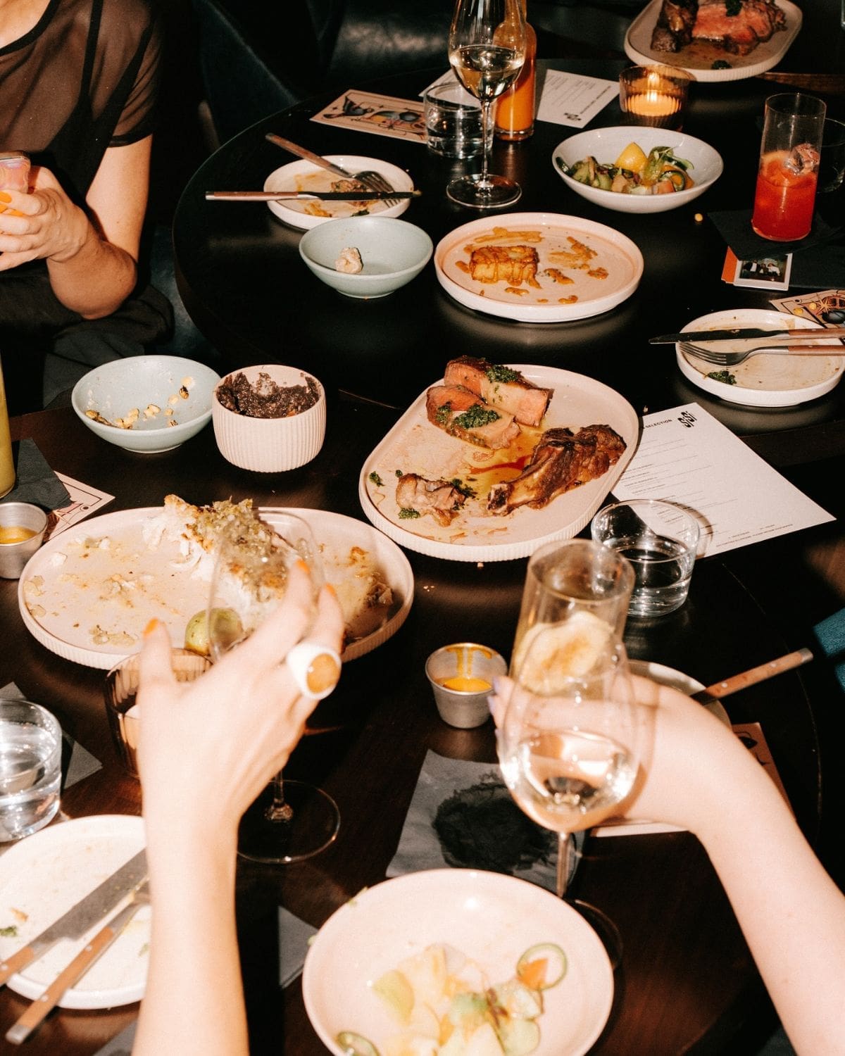 Friends sharing plates, wine and cocktails around a candlelit dinner table in Glasgow — a stylish pick for a hen weekend or girls’ dinner in the city.