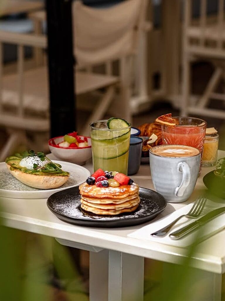 Pancakes, coffee and brunch plates on a table at Café Montesol in Ibiza, casual daytime dining for a hen weekend.