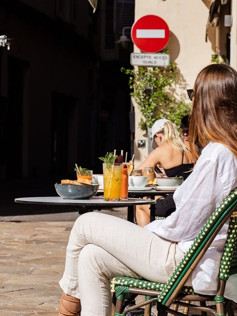 Girls sitting outside at Lili’s in Palma Old Town, drinks on the table and sunny terrace seating, a pretty brunch stop for a hen weekend.