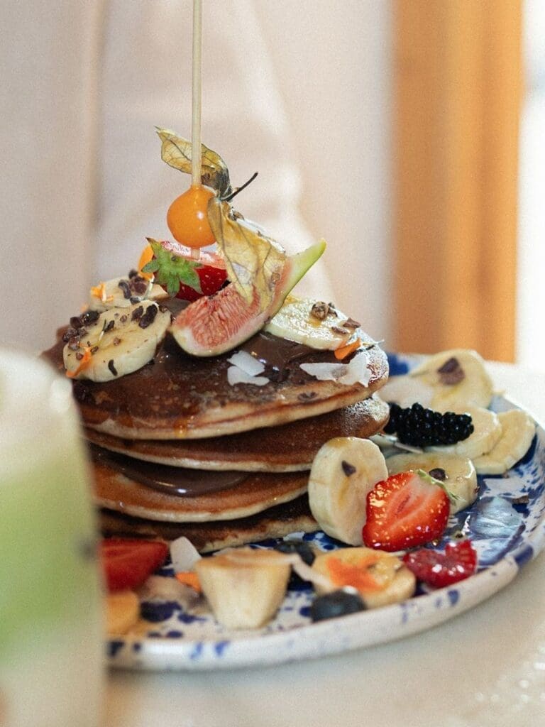 Stack of pancakes topped with fresh fruit and syrup at Mama Carmen’s in Palma, a vegan-friendly brunch spot ideal for hens with dietary requirements.