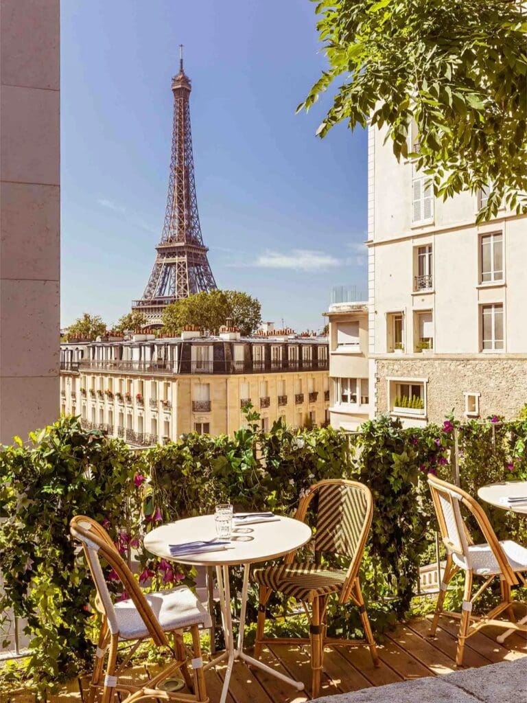 Sunlit Paris terrace with bistro tables and chairs overlooking the Eiffel Tower, ideal for a scenic brunch or lunch stop on a girls’ weekend.