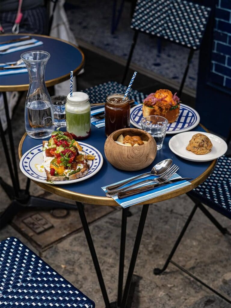 Bright, design-led interior at Kozy Paris with curved seating, soft tones and floral centrepieces, ideal for a wholesome brunch stop on a girls’ weekend.