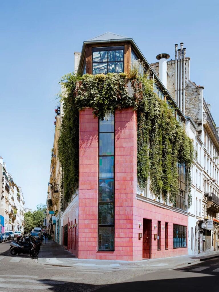 Pink corner building covered in greenery on a Paris street, with large windows and rooftop seating — a standout brunch spot for a girls’ weekend.