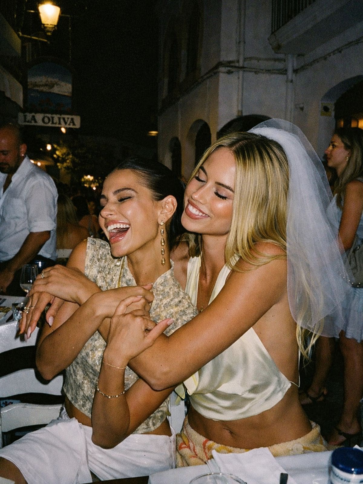 Bride and bridesmaid laughing together at an Ibiza hen weekend dinner, capturing the energy of a night that turns into a party.