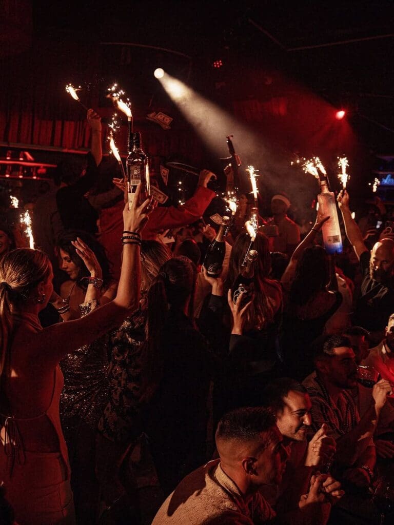 Hen party group at Lío Ibiza raising champagne bottles with sparklers during a high-energy, nightclub-style dinner on a girls’ weekend.