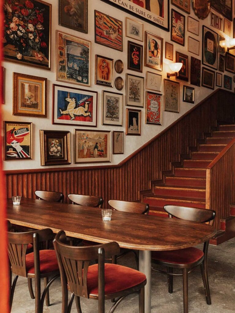Cosy dining room at Leonetta in Lisbon featuring framed artwork and wooden tables for a lively girls’ night.
