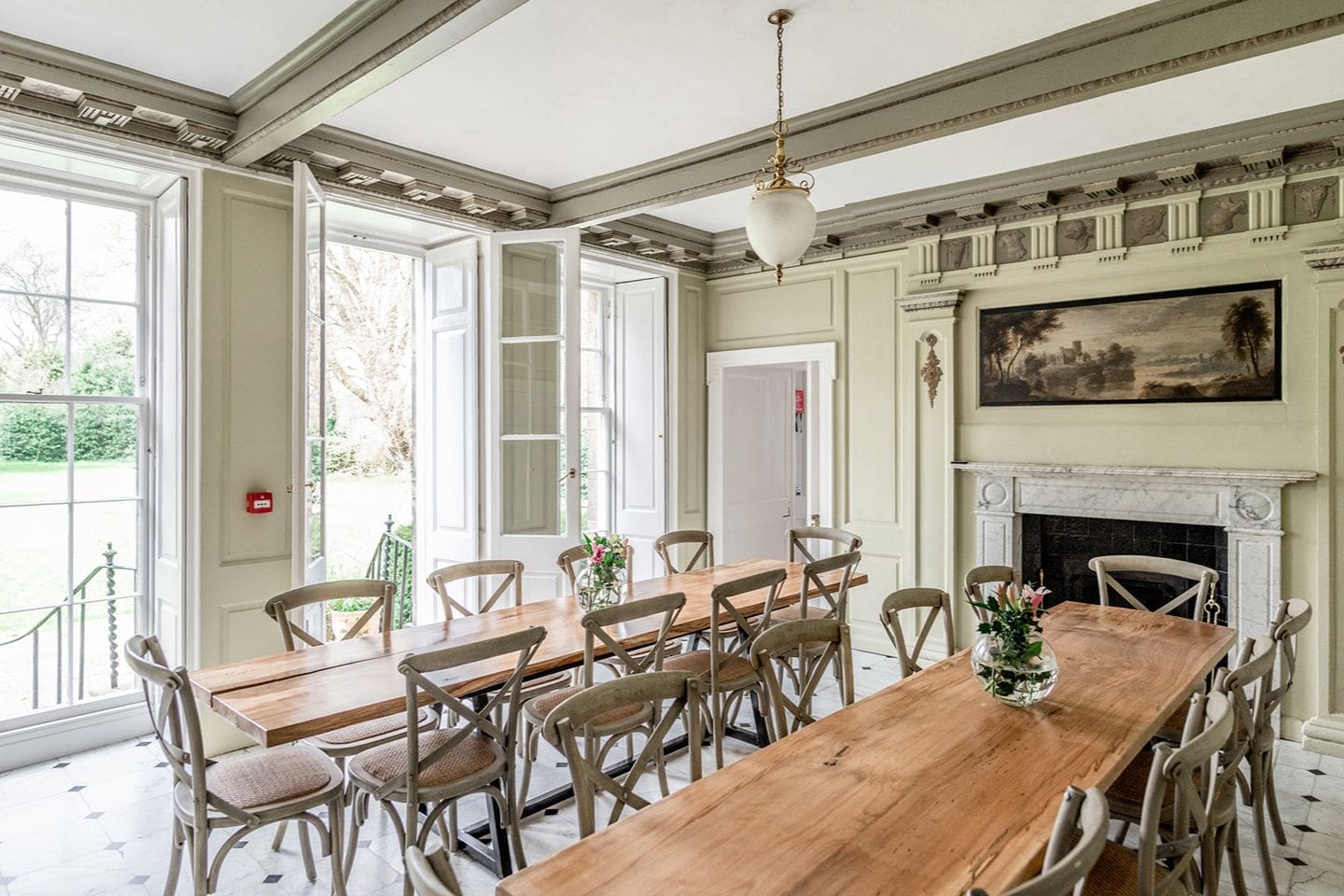 Elegant dining room at Drylaw House Edinburgh with long wooden tables, high ceilings and garden views, ideal for large group stays