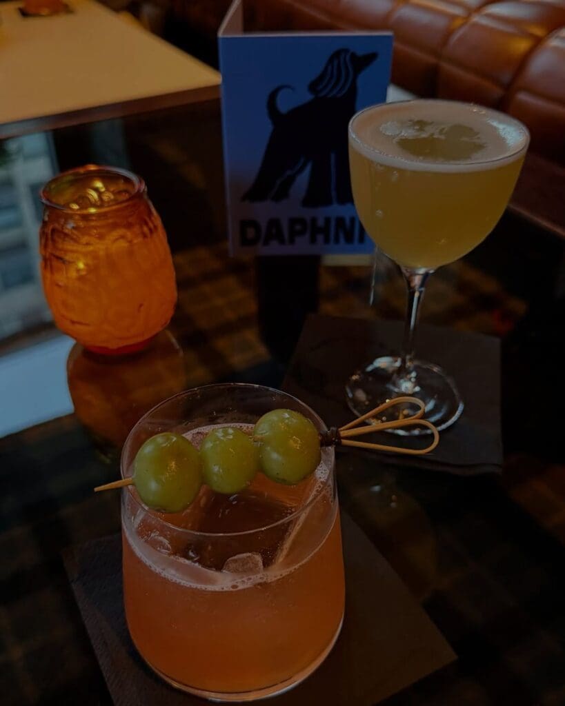 Cocktails on a low-lit table at Daphne in Dublin, with soft candlelight and a polished bar setting for drinks on a Dublin hen weekend.