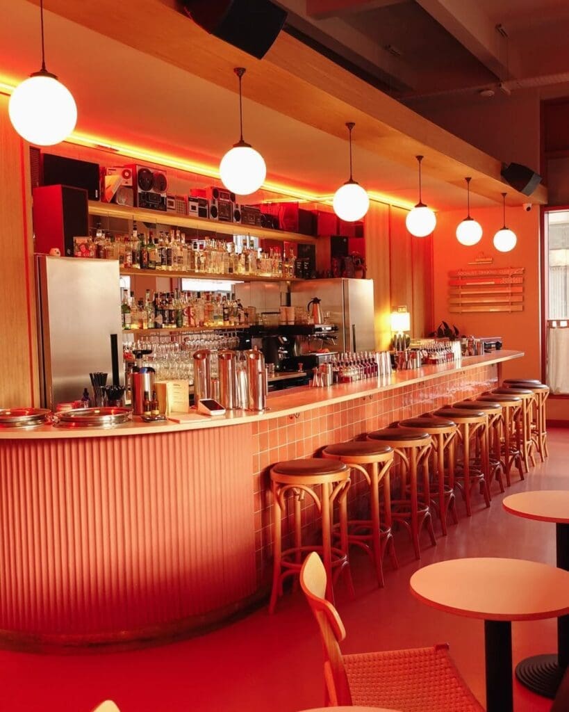 Coral-toned bar inside Sister Ray in Liverpool, with globe pendant lights, vinyl details and sleek counter seating for cocktails on a Liverpool girls’ night out.