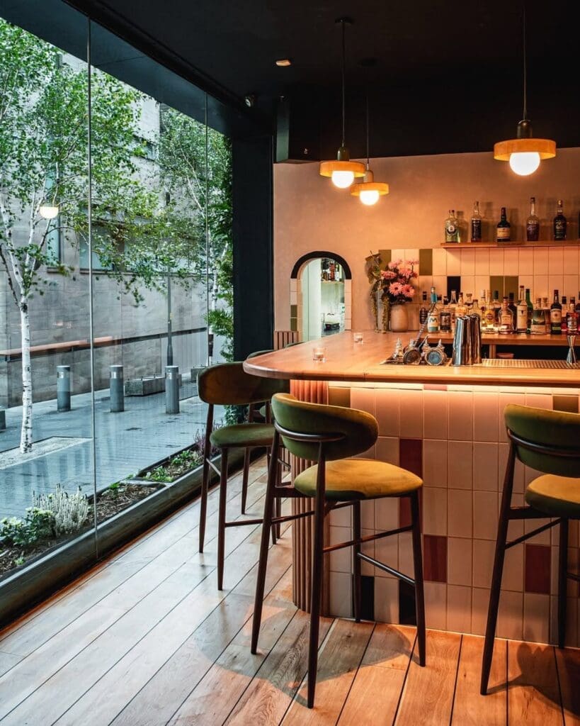 Pastel-tiled bar at Posie in Manchester, with warm pendant lighting, green stools and floor-to-ceiling windows for a polished girls’ night out in Manchester.