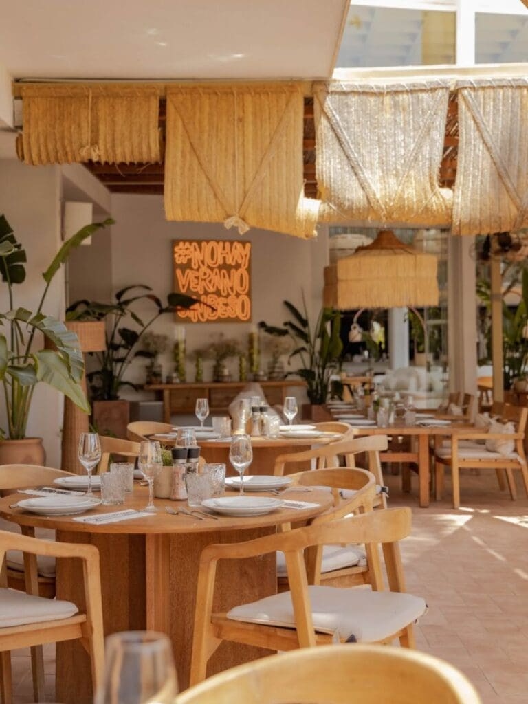 Palma hen activities image of Beso Beach Mallorca, with a sunlit dining room, wooden tables, fringe lampshades and relaxed beach club-style interiors.