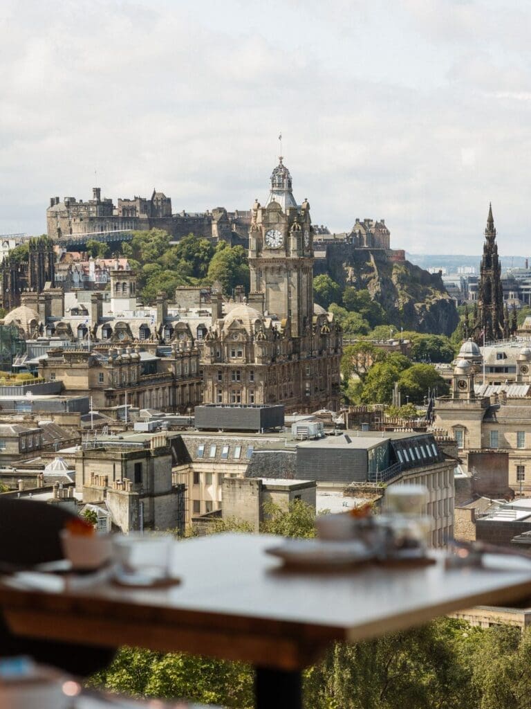 A restaurant table at Cafe Calton overlooking Edinburgh’s skyline, with Edinburgh Castle, the Balmoral clock tower and the Scott Monument in view — a scenic pick for Edinburgh hen do activities.