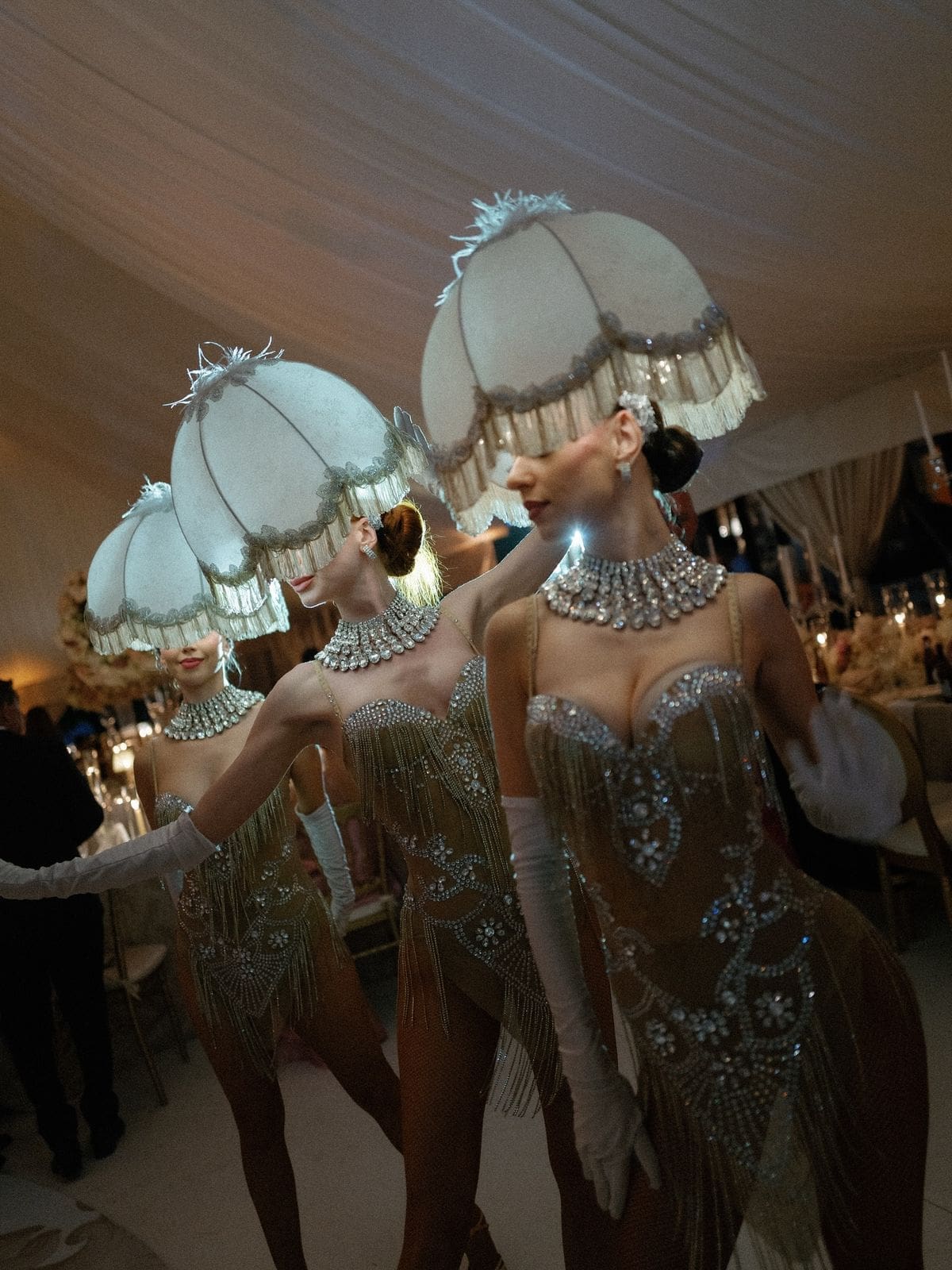 Glamorous performers in crystal-embellished costumes and fringed lampshade headpieces entertain guests at a theatrical Liverpool hen do activity.