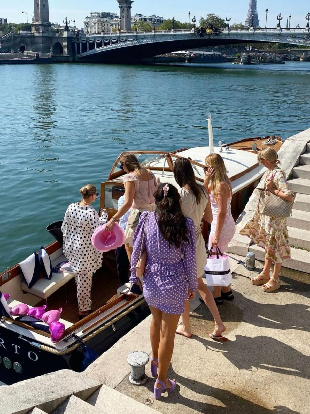 Paris hen do activities image of a group boarding a private boat on the River Seine, with the Eiffel Tower and Paris bridges in the background.