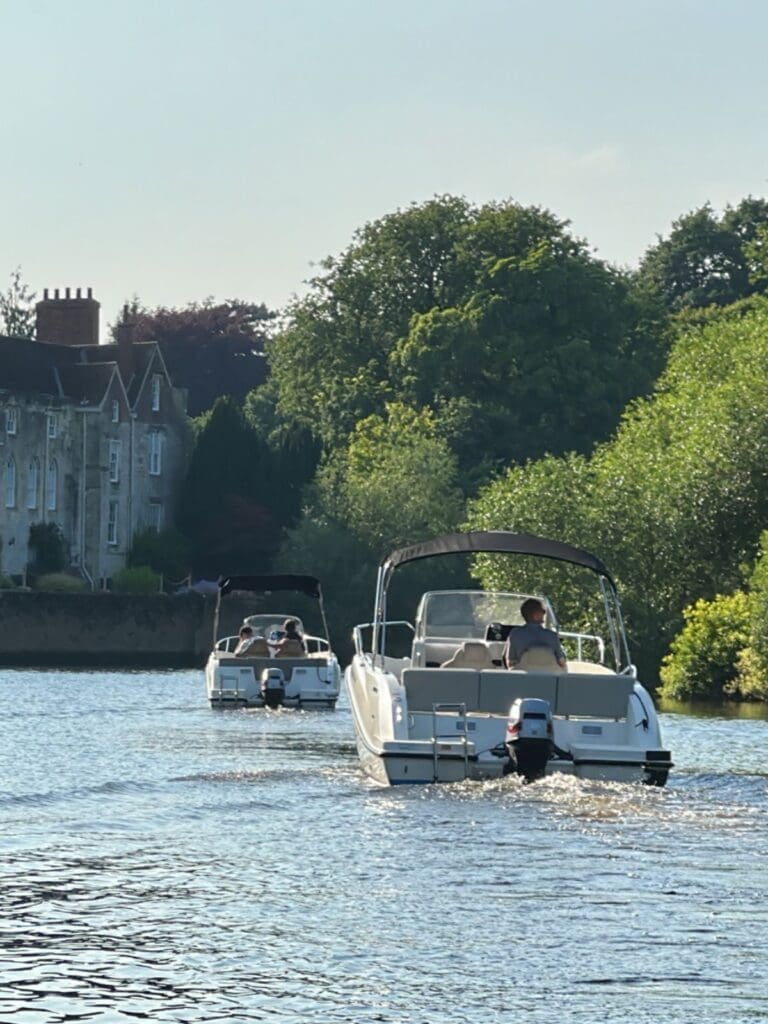 Boat hire on the River Ouse in York, with small motorboats on the water and leafy riverbank views, featured as a relaxed York hen do activity.