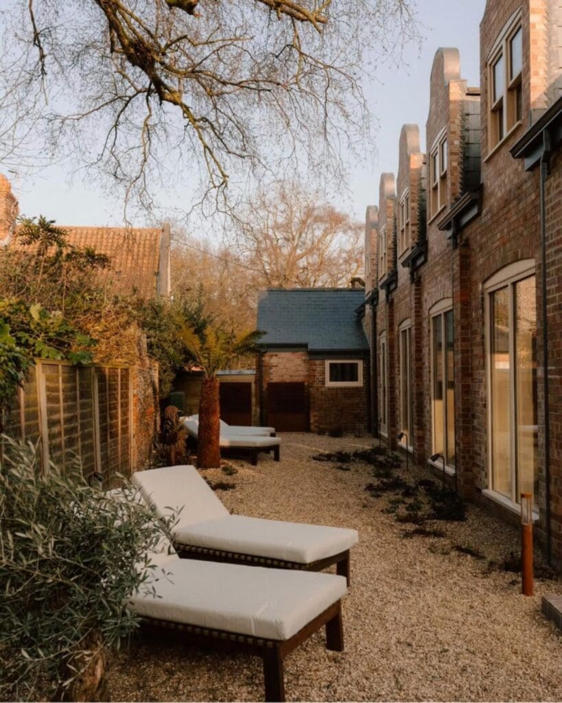 Courtyard terrace at ARC Next The Sea with sun loungers, landscaped gravel gardens and modern coastal interiors — a relaxed luxury retreat for group stays, girls’ weekends and quieter hen weekends by the sea.