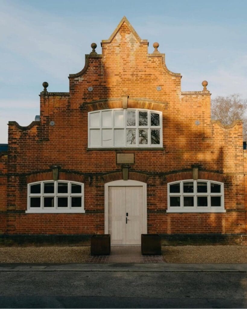 Restored red brick exterior at ARC Next The Sea with Dutch-gable architecture and warm golden-hour light — a design-led coastal group stay for a luxury hen weekend or girls’ trip.