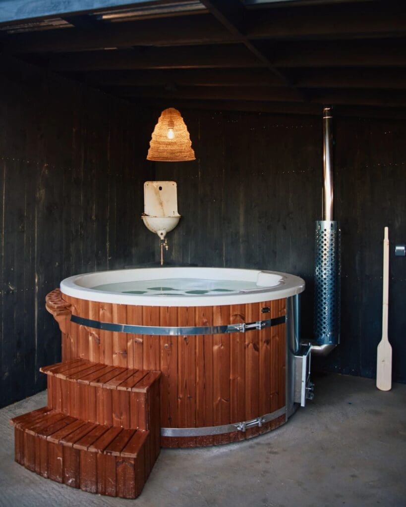 Wood-fired outdoor hot tub at Bonnington Farm with dark timber interiors and spa-style countryside details — a cosy group stay feature for a relaxed hen weekend or girls’ trip in Scotland.