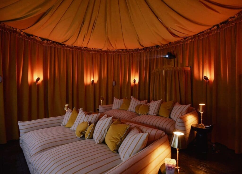 Cinema room at Bonnington Farm with oversized striped loungers, draped tented ceilings and low-lit interiors — a luxury countryside retreat designed for cosy nights in on a hen weekend or girls’ trip.