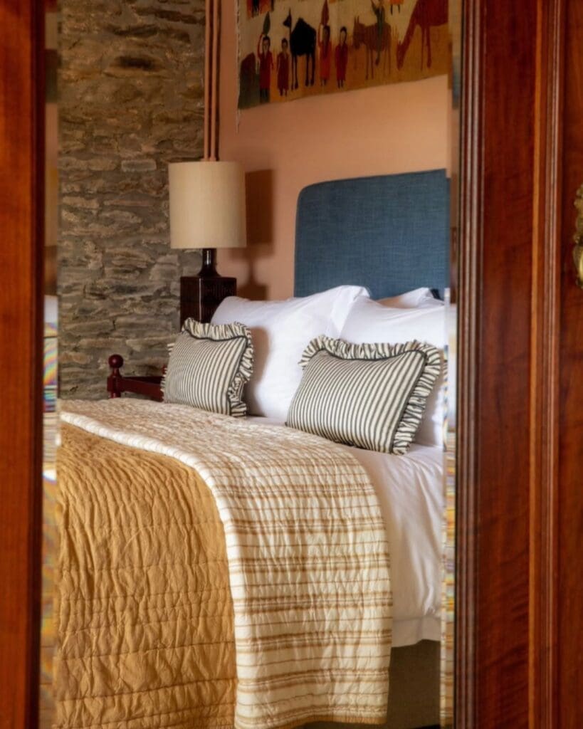 Bedroom interior at Cottage Orné with exposed stone walls, layered textiles and warm country house styling — a cosy luxury stay for a relaxed hen weekend or girls’ trip in the countryside.