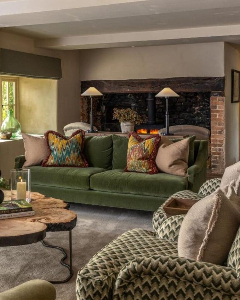 Cosy lounge interior at Louma Farm & Retreat with a green velvet sofa, wood-burning fireplace and warm countryside cottage interiors — a luxury group stay for a relaxed hen weekend or girls’ trip in Dorset.