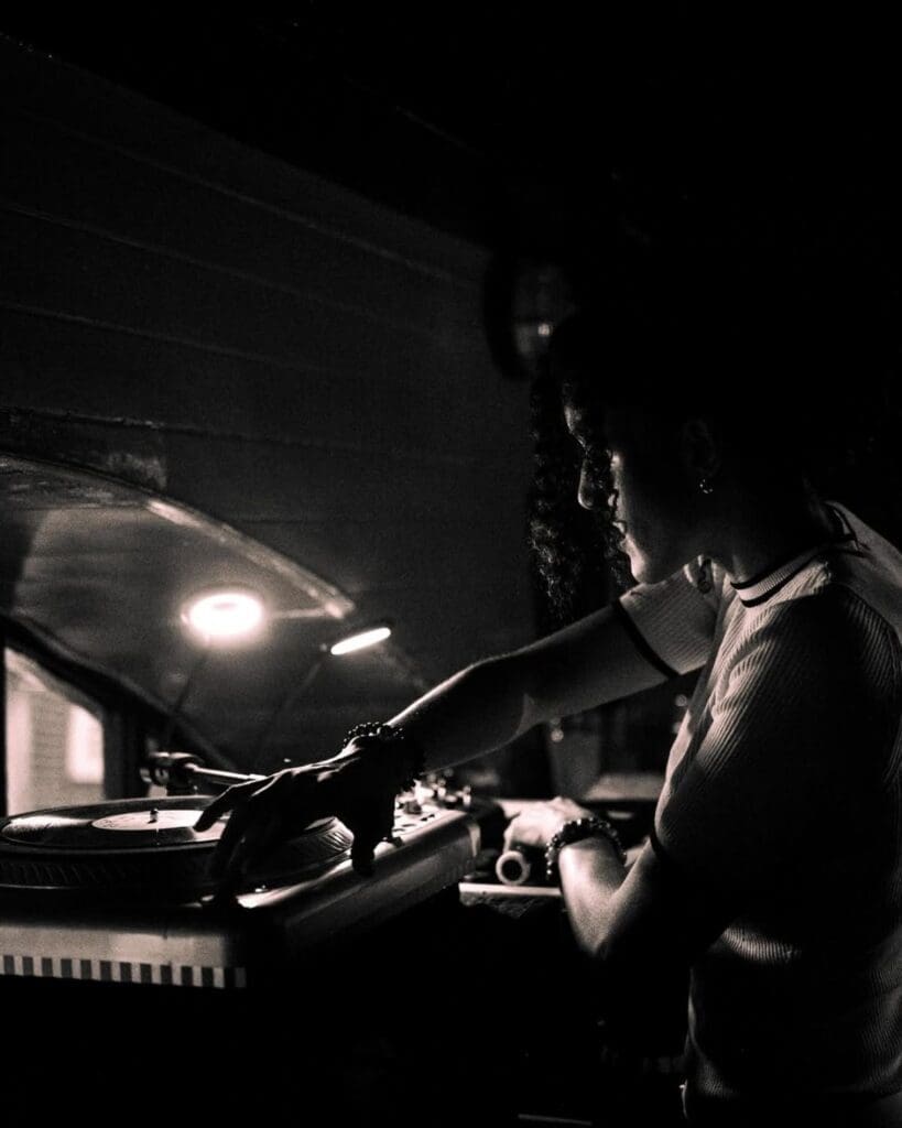 DJ playing vinyl at Fortune of War in Brighton, captured in a moody black-and-white photo inside the seafront bar during a Brighton hen weekend.