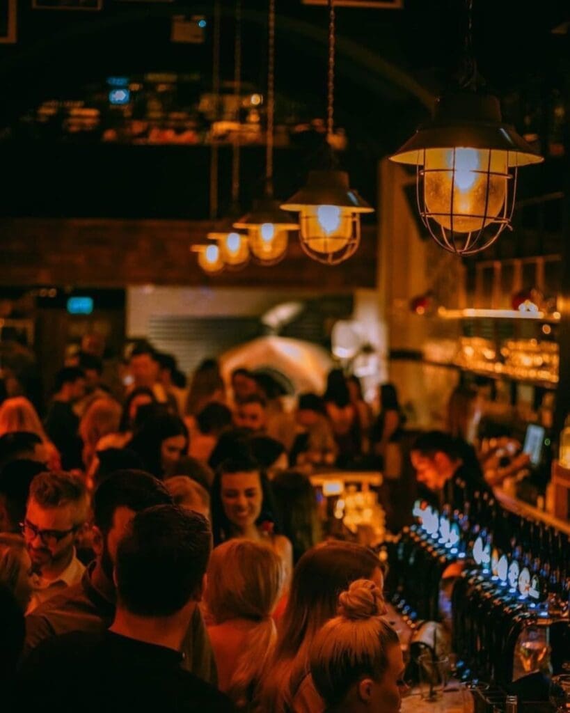 A packed evening at NoLIta Dublin, with guests gathered around the glowing bar beneath warm hanging lights — a lively choice for cocktails and going out-out in Dublin.
