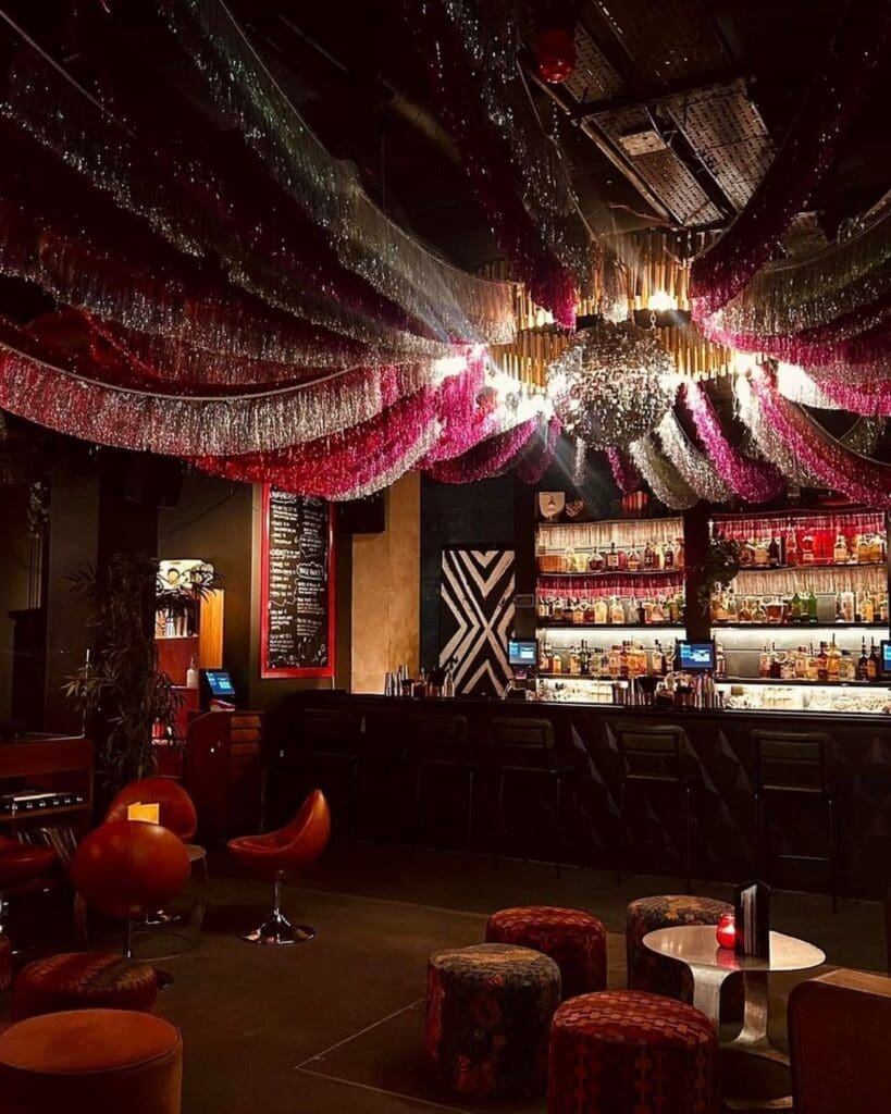 Interior of Little Scarlet Door in Soho, London, with colourful décor and a house-party feel, featured as a fun cocktail bar option for London hen activities.