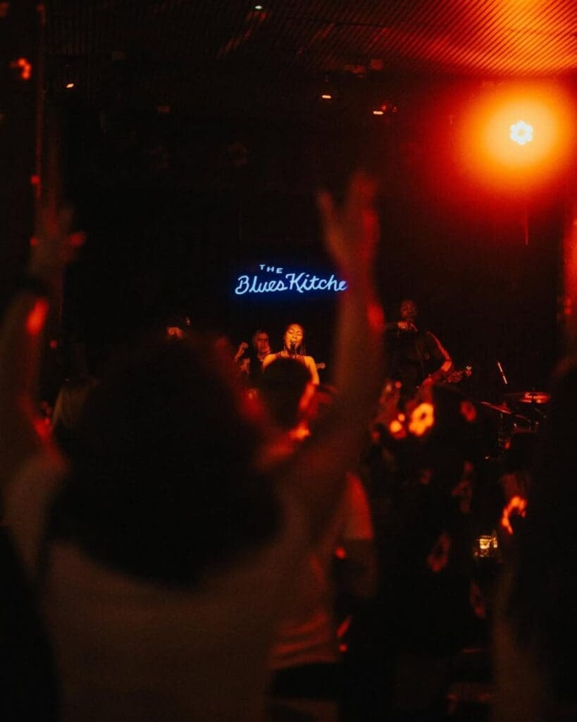 A live band performing at The Blues Kitchen in Shoreditch, London, with the crowd dancing under warm red stage lights — a lively late-night pick for a London hen weekend or girls’ trip.
