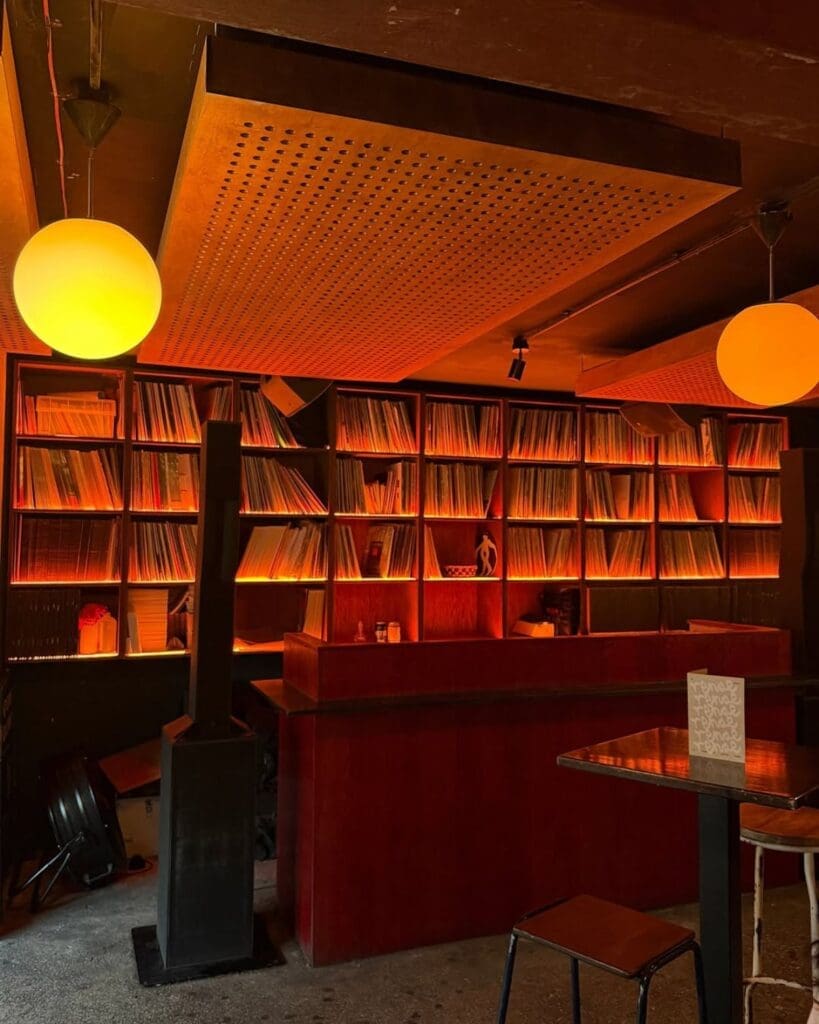 The warm, vinyl-lined interior of Renae in Manchester, with glowing orange lighting, a record-filled back wall and an intimate DJ booth — a cool late-night spot for a Manchester hen weekend.