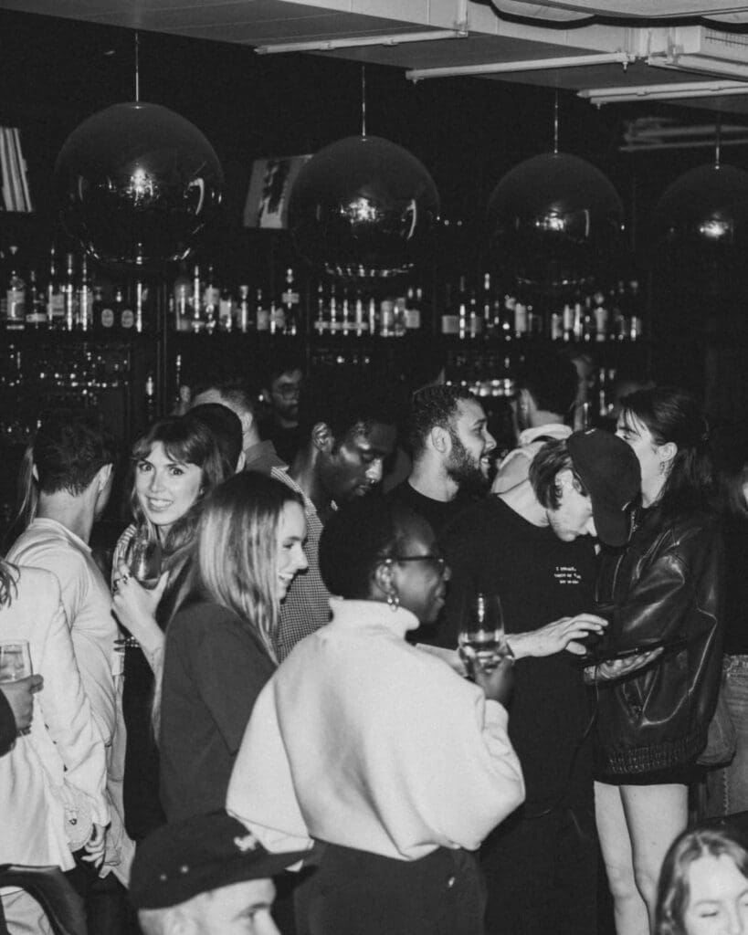 A busy night at Side Street in Manchester, with guests drinking and chatting beneath oversized pendant lights in the softly lit bar — a stylish late-night pick for a Manchester hen weekend.