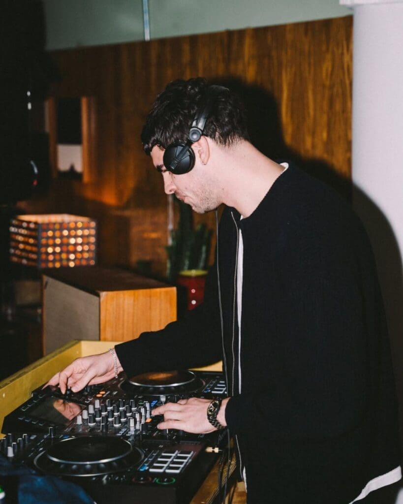 A DJ playing at Side Street in Manchester, mixing behind the decks in the warmly lit bar — a late-night spot for cocktails, music and going out-out on a Manchester hen weekend.