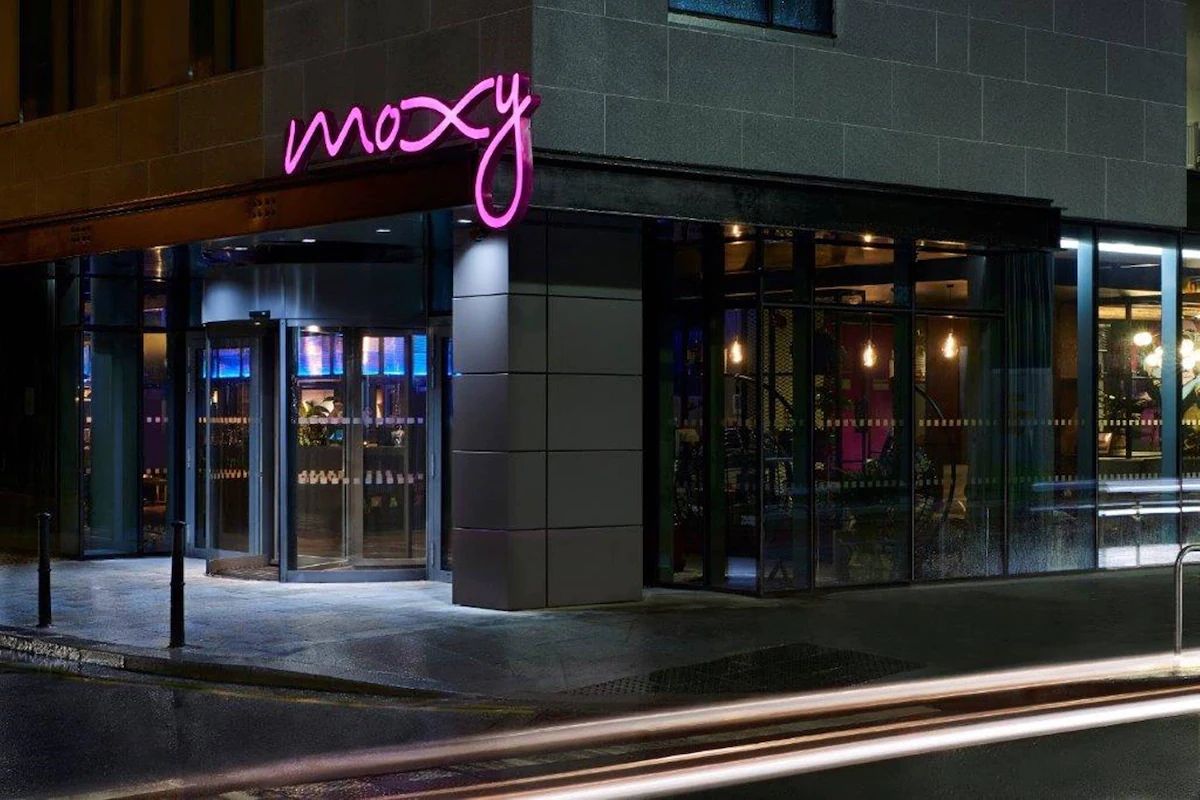 Exterior of Moxy Dublin City at night, a centrally located hotel for a hen weekend in Dublin with the hotel’s pink illuminated sign.