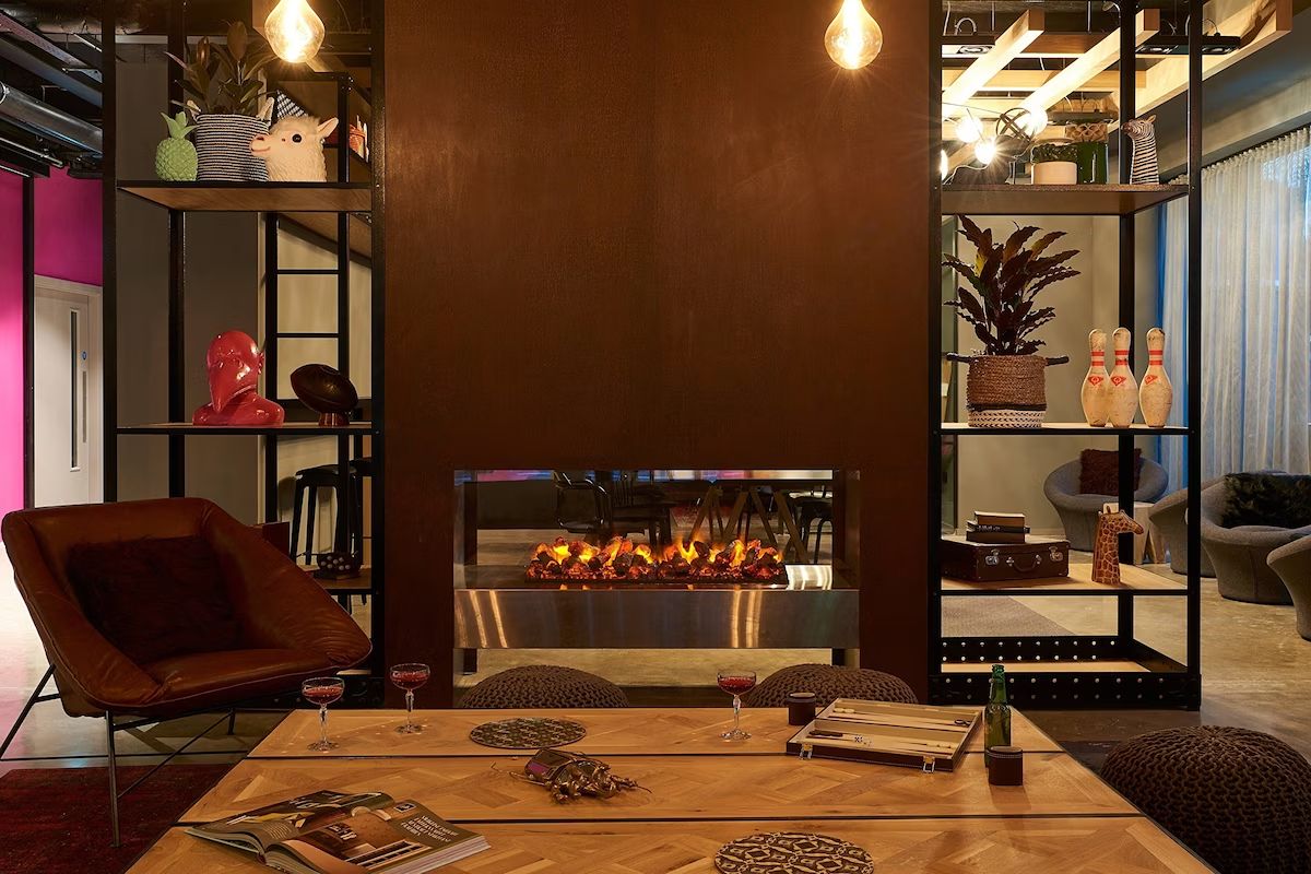 Lounge area at Moxy Dublin City with a fireplace, games and relaxed seating, ideal for a laid-back hen weekend in Dublin.