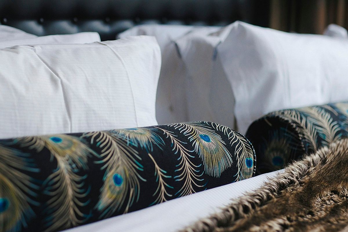 Peacock-print cushions and luxe bedding at The Rex Newcastle, a theatrical five-star Newcastle city-centre hotel.
